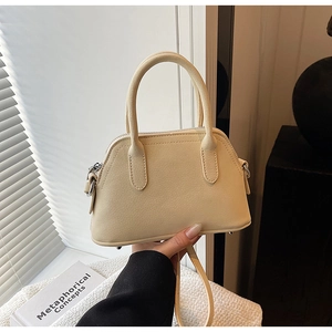 Detail of cream lychee leather handbag with round handles and metal hardware