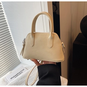 Detail shot of mini cream crossbody bag with litchi texture and minimalist top handles