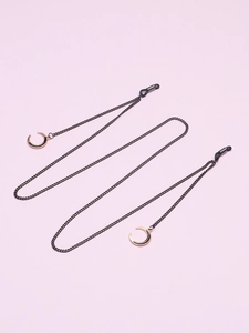 Détail d'une chaîne à lunettes en métal noir avec pendentifs lune dorée et boucles