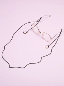 Détail d'une chaîne à lunettes noire avec pendentifs lune dorés et boucles en silicone