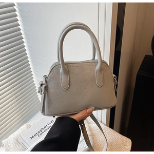 Detailed view of light gray shell handbag with lychee pattern and adjustable strap