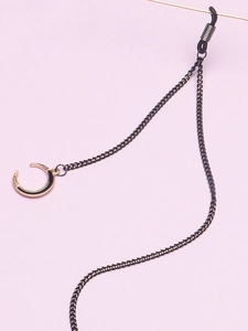 Détail d'une chaîne de lunettes noire avec un pendentif en croissant de lune doré