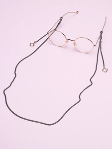 Detail of black metal eyewear chain with golden square pendants on lavender background
