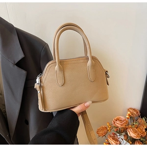 Detail of a beige litchi pattern shell bag with silver hardware and top handles