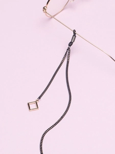 Detail of minimalist black eyewear chain featuring a square geometric pendant and rubber grip