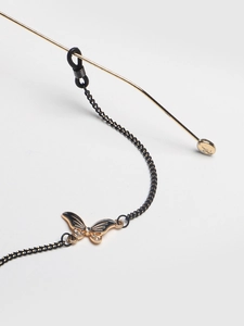 Detail of black non-slip metal eyewear chain with rhinestone butterfly charm on gold arm