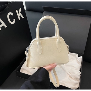 Detail of a creamy beige leather crossbody bag with lychee texture in a luxury gift box