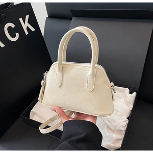 Detail of off-white shell bag with lychee texture held near premium gift box