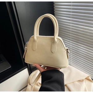Detail of beige litchi grain shell bag featuring silver metal hooks and sturdy handles