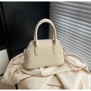 Detail of cream shell bag featuring lychee grain leather and cylindrical double handles
