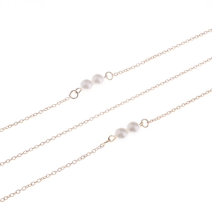 Détail de la chaîne de lunettes dorée ornée de perles blanches et maillons fins