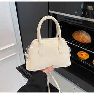 Detail of cream lychee texture handbag with metal zipper and adjustable strap