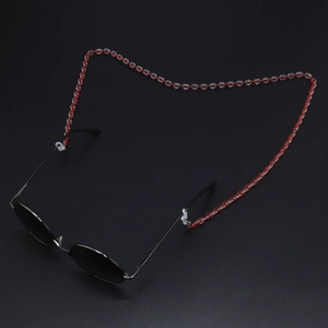 Detail of red and white acrylic eyewear chain on black oval sunglasses frame