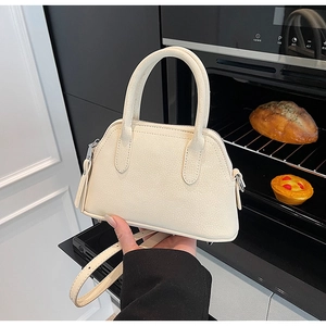 Close-up of a cream white pebble-grain handbag featuring silver hardware and top handle