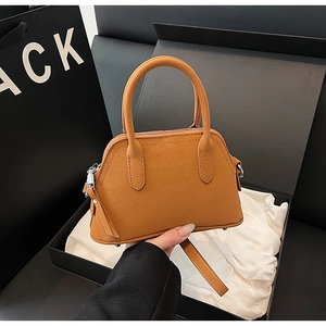 Close-up of caramel lychee textured leather handbag with silver hardware and gift packaging