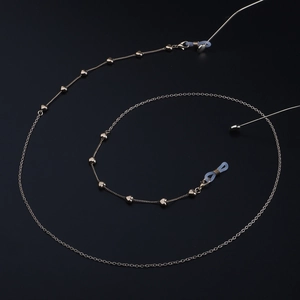 Chaîne de lunettes dorée avec maillons en cœur et boucles réglables sur fond sombre