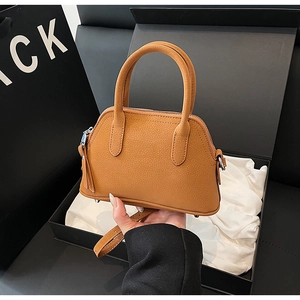 Detailed close-up of camel shell bag showing lychee grain leather texture and top handle