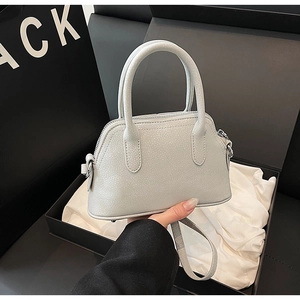 Close-up of light grey litchi grain leather handbag with silver hardware and shoulder strap