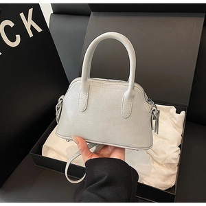 Detail of light gray lychee grain leather handbag with silver hardware and top handles