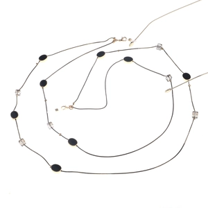 Detail van de gouden slangketting met zwarte ovale stukjes en transparante kralen
