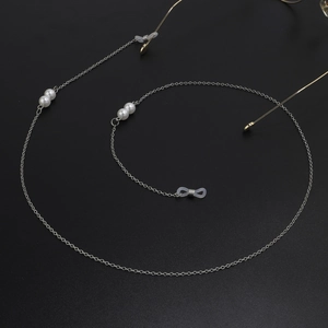 Détail de la chaîne à lunettes en argent avec perles blanches et boucles en silicone noir