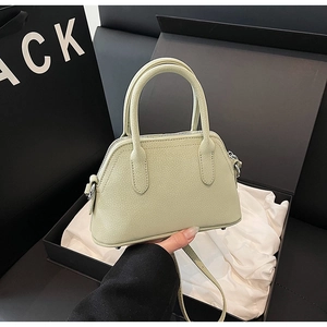 Detail of mint green pebble leather shell bag with top handles and adjustable strap