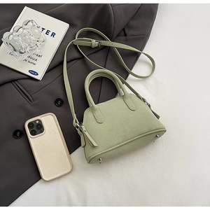 Detailed close-up of light green lychee textured handbag with protective base studs