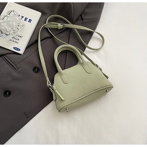 Detail of mint green shell bag with pebble leather texture and silver bottom studs