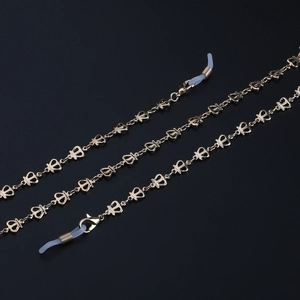 Golden eyewear chain with hollow crown links and non-slip silicone loops on black background