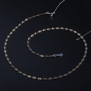 Golden crown-shaped metal eyeglass chain with non-slip silicone loops on black background