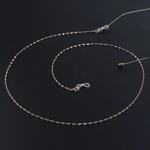 Détail d'une chaîne à lunettes dorée avec maillons lèvres et boucles en silicone