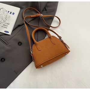 Close-up of brown litchi-textured leather mini bag with silver metal bottom studs