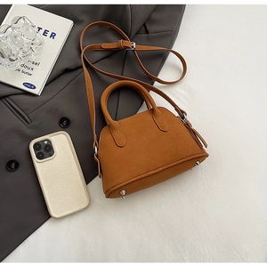 Detail of caramel brown mini Boston bag showing leather texture and metal bottom studs