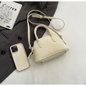 Detail of cream leather shell bag with lychee texture and metallic bottom rivets
