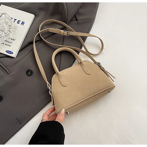 Detail of beige litchi grain leather bag with double handles and protective metal studs