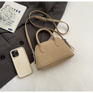 Detail view of khaki shell bag with litchi grain and bottom metal studs and phone