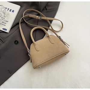 Top view of beige lychee pattern handbag on a grey blazer and book background