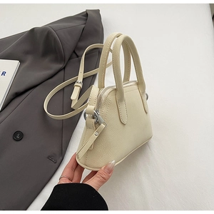 Close-up of cream white pebble leather shell bag with silver zipper and slim strap