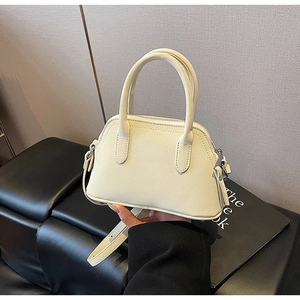 Close-up of cream white lychee leather texture and silver hardware on a mini handbag