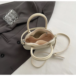 Top-down view of cream mini shell bag showing internal pockets and zip closure
