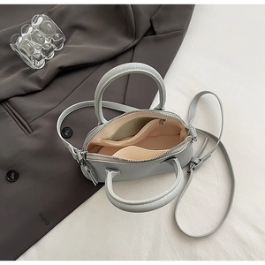 Detail view of mini shell bag interior with pink lining and metal zipper closure