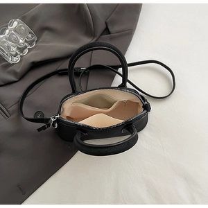 Detail view of the interior beige lining and metal zipper of the black mini crossbody bag