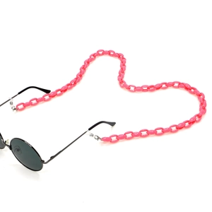 Macro detail of peach pink acrylic eyeglass chain in a heart shape on white background