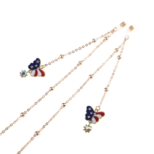 Detail of gold glasses chain with enamel butterfly charm and faux gemstone accents