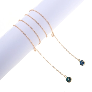 Golden eyewear chain with star and moon enamel pendants on a white cylindrical display