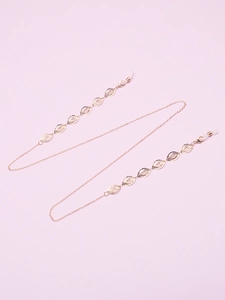 Detail of golden eyeglass chain with hollow oval links and rubber loops on violet background