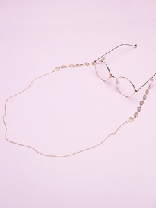 Detail of gold-plated eyeglass chain featuring hollow leaf charms and delicate metal links