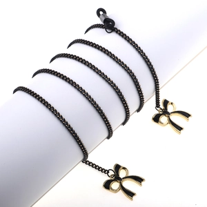 Fashionable black and gold eyewear chain with elegant bow charms and rubber loop ends