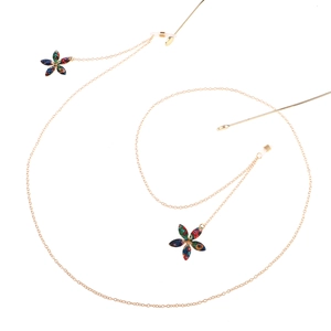 Catena per occhiali dorata con ciondoli a fiori colorati e asole in silicone su sfondo bianco
