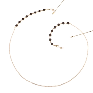 Elegant gold metal eyeglass chain featuring polished black circular beads on white background